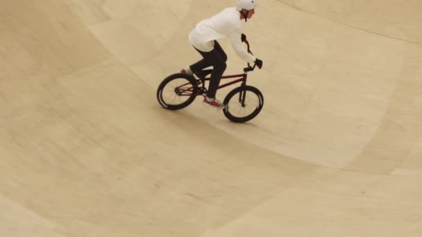 Młody człowiek jeżdżący na rowerze BMX na rampie na placu treningowym — Wideo stockowe