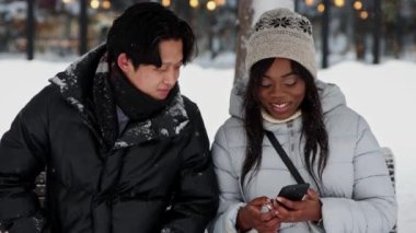 Genç siyahi kadın, Asyalı erkek arkadaşına telefonunda fotoğraflarını gösteriyor.
