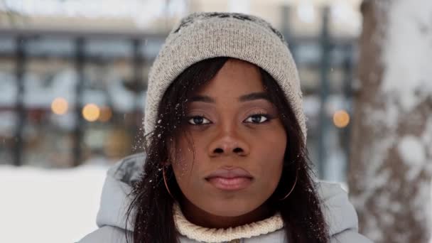 Jovem mulher negra fica na floresta de inverno e sorri para a câmera — Vídeo de Stock