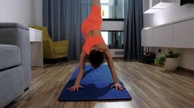 Evde spor yapmak - genç bir kadın yoga minderinde bacakları için spor yapıyor.