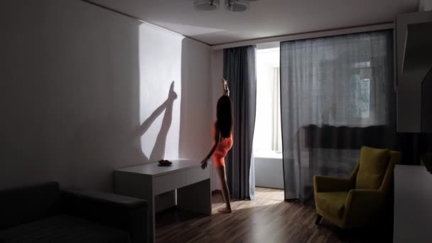 Fitness à la maison - jeune femme étirant sa jambe avec maintien à la table dans la chambre avec rideaux fermés — Video