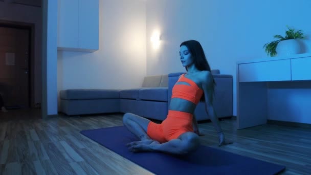 Fitness doma v modrém osvětlení - mladá žena dělá fitness cvičení na podložce jógy — Stock video