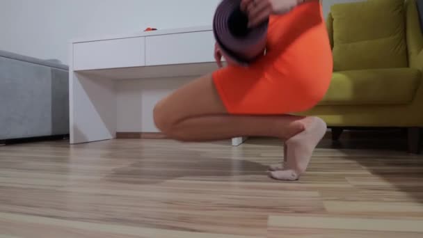 Fitness em casa - jovem mulher estabelece o tapete de ioga no chão — Vídeo de Stock