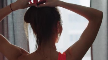 Genç bir atlet kadın saçını atkuyruğundan ayırıyor.