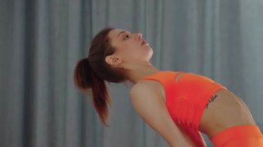 Genç, güzel bir kadın yoga minderinde geriye doğru eğiliyor.