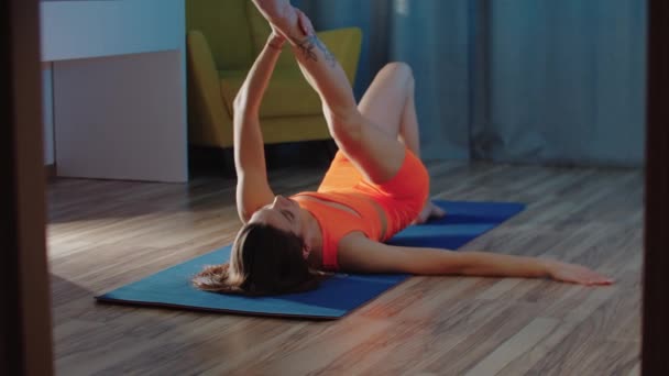 Genç kadın bacaklarını yoga mat germe — Stok video