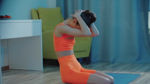 Jovem mulher bonita em terno de esportes laranja aquecendo seu pescoço e corpo — Vídeo de Stock
