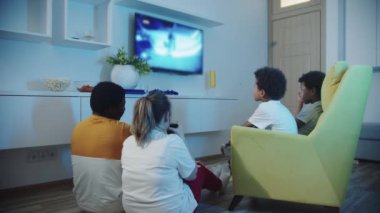 Çok ırklı bir aile oturma odasında oturup televizyon izliyor.