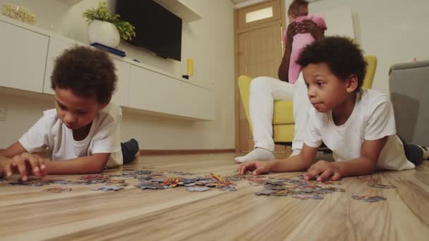 Black family in the room - brothers do a pazzle and only father playing with baby daughter — Stock Video