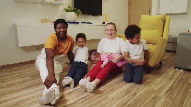 Multi race family sitting on the floor in the room and looking in the camera — Stock Video