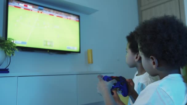 Dwóch czarnych chłopców gra w piłkę nożną w telewizji. — Wideo stockowe