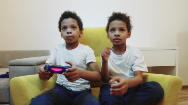 Zwei kleine schwarze Jungen Brüder spielen ein Spiel und nehmen einander den Steuerknüppel weg — Stockvideo