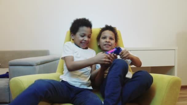 Dois meninos negros pequenos irmãos jogando um jogo e lutando por um joystick — Vídeo de Stock