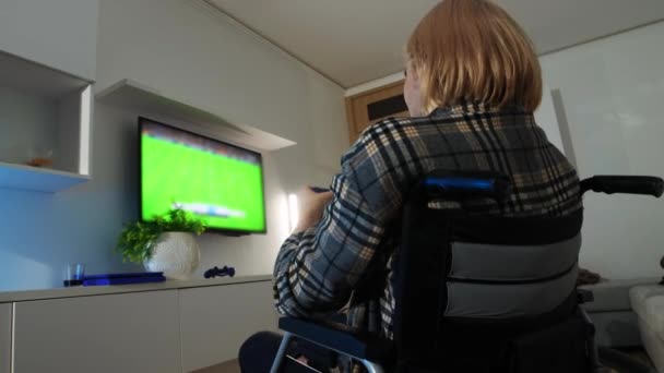 Młody człowiek na wózku inwalidzkim gra w piłkę nożną w telewizji — Wideo stockowe