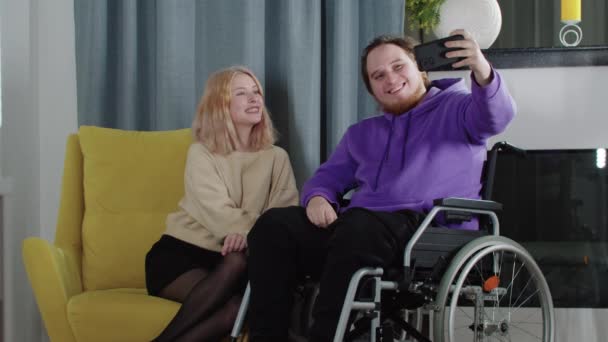 Szczęśliwa para blondynki i mężczyzna na wózku inwalidzkim robiący selfie przez telefon — Wideo stockowe