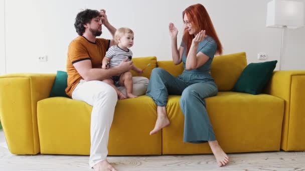 Familjen sitter på gul soffa och barnet håller pennor — Stockvideo