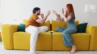 Aile sarı koltukta oturuyor ve ebeveynler patty-cake oynuyor.