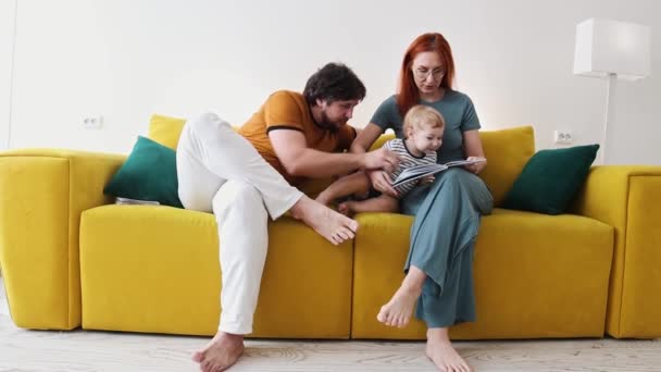 一家人坐在黄色的沙发上，一起看书 — 图库视频影像