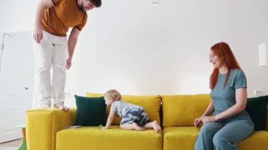 Sarı koltukta bir aile - bebek bir zambak tutuyor ve kanepede sürünüyor