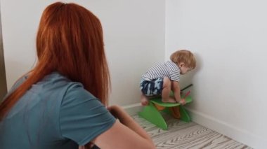 Çocuk sandalyesine tırmanmaya çalışan küçük bir çocuk.