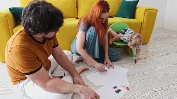 床に座ってカラフルなクレヨンで絵を描く家族 — ストック動画