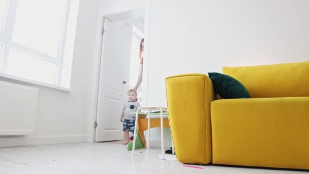 Anne, küçük oğluyla oturma odasında yürüyor ve babasının yanından geçiyor. — Stok video