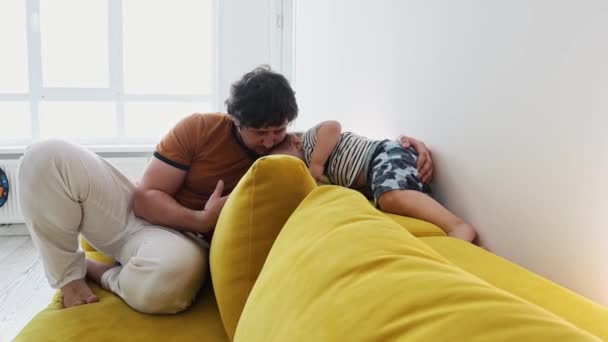 Erwachsener Vater sitzt mit seinem kleinen Sohn auf der Couch — Stockvideo