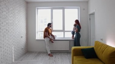 Küçük oğlumuzla beyaz salonda oynayan mutlu bir aile.