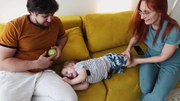 Glückliche Familie verbringt Zeit auf der Couch und Mutter spielt mit ihrem kleinen Sohn — Stockvideo