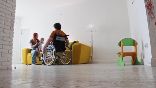 Ginger žena a její malý syn dává plácnutí na jejich manžela a tátu na invalidním vozíku — Stock video
