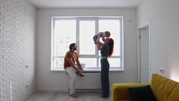 Glückliche Familie mit kleinem Sohn im weißen Wohnzimmer vor dem Fenster — Stockvideo