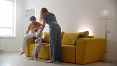 Aktif bir bebek, ebeveynlerinin gözetiminde kanepenin yanına koşar.