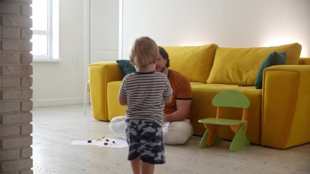 Słodkie dziecko spacery do jego ojciec siedzi na podłodze i daje mu jabłko — Wideo stockowe
