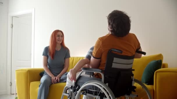 Мужчина в инвалидном кресле играет со своим ребенком и его женой, наблюдая за ними — стоковое видео