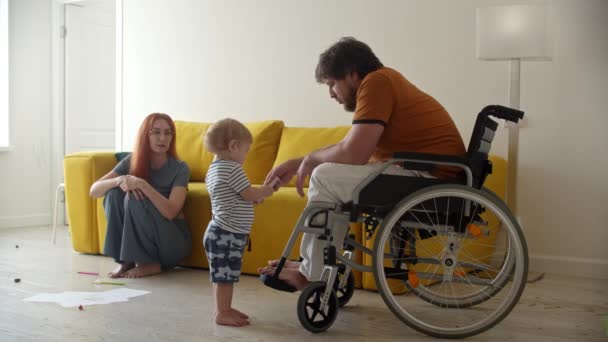 Mannen i rullstol hjälper sin lille son att fixa en TV-fjärrkontroll — Stockvideo