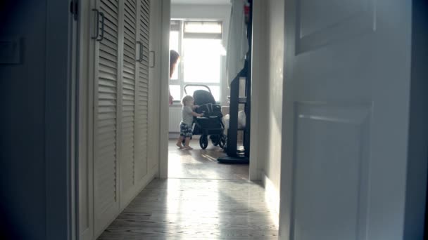 Küçük bir bebek bebek arabasına binmeye çalışır ve annesi dikkatini dağıtır. — Stok video
