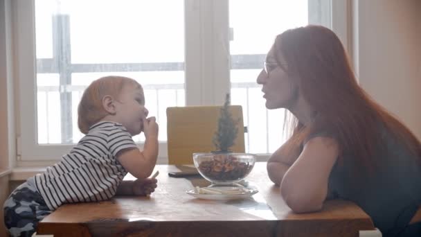 Pequeno bebê alimentando sua mãe com pedaços de maçã à mesa — Vídeo de Stock
