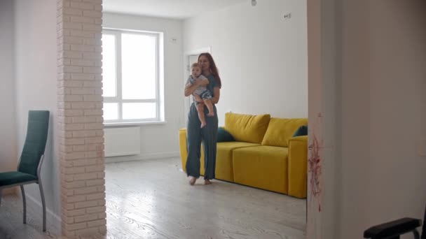 A nő kisbabát hoz a dolgozó férjének a konyhában. — Stock videók