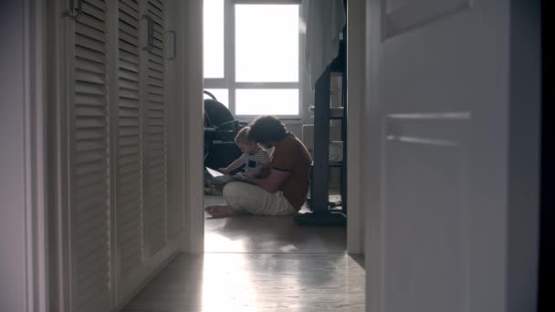 Einsamer Vater sitzt mit seinem Baby auf dem Boden und liest ein Buch — Stockvideo