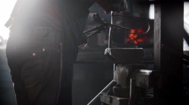 Demirci atölyesi - bir adam metal nesne üzerinde basınçlı makine kullanarak çentik atıyor