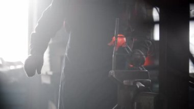 Demirci atölyesi. Bir adam, ısıtmalı metal parçaları prezervatifin içine koyar.