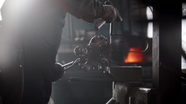 Blacksmith workshop - a man holding metal chandelier with pincers standing near the pressing machine — Stock Video