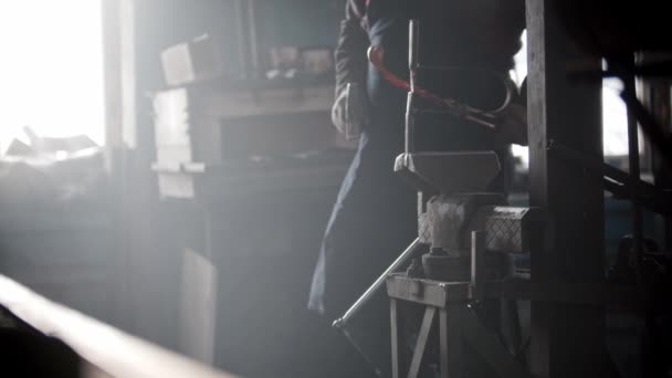 Blacksmith workshop - a man puts heated metal detail in the pressing retainer and hits it with a hammer — ストック動画