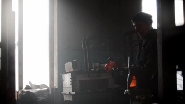Кузнечная мастерская - мужчина достает металлическую люстру из духовки с клешнями — стоковое видео
