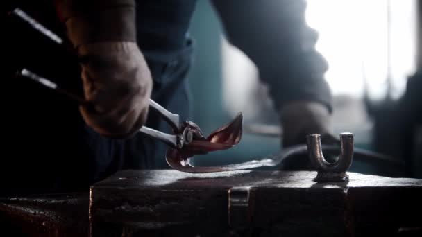 Oficina de ferreiro - um homem dobrando o metal aquecido em forma de folha — Vídeo de Stock
