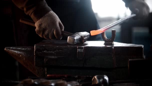 Smedja verkstad - en man böjer en bit metall med att slå den med en hammare — Stockvideo