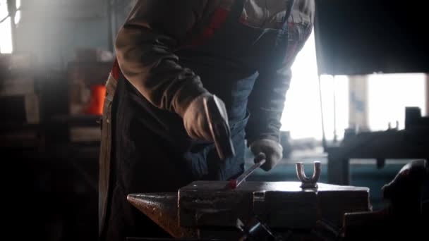 Smedja verkstad - en man smed böjer en bit metall med att slå den med en hammare — Stockvideo