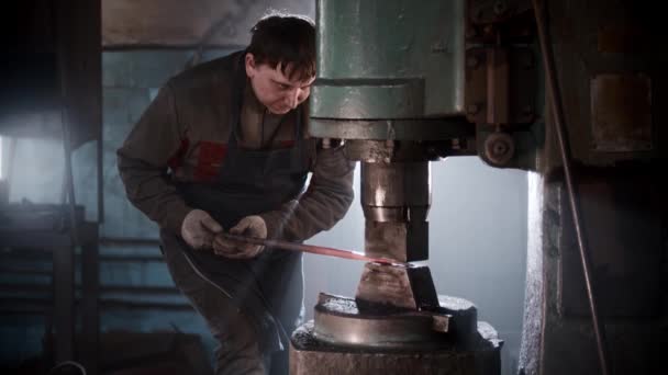 Officina di fabbri - un uomo che lavora con metallo riscaldato utilizzando una pressa automatica — Video Stock