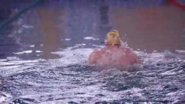 Sarı şapkalı bir adam havuzda yüzüyor.