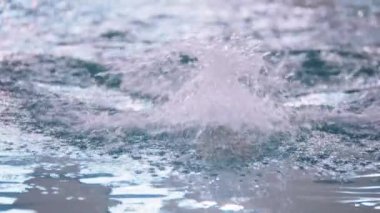 Sarı şapkalı bir adam havuzda yüzüyor.